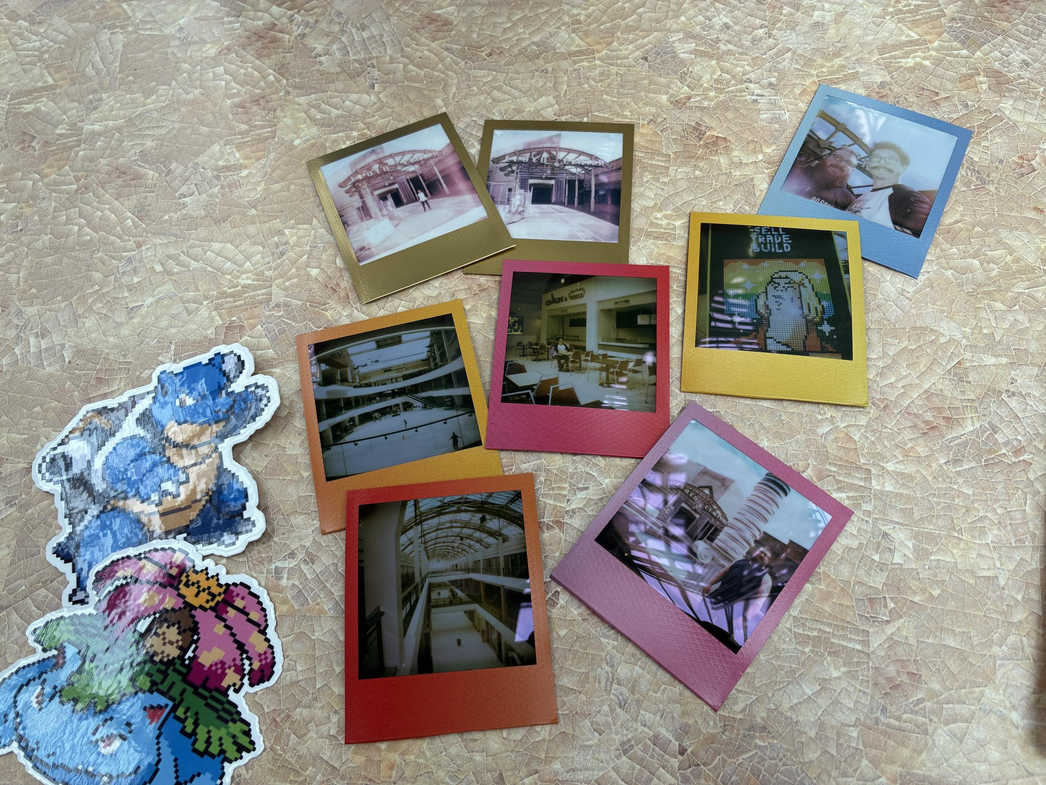 A collection of vintage-style polaroid photographs featuring various indoor scenes and selfies, arranged on a textured background. Additionally, there are colorful stickers of cartoon characters—a blue creature and a green creature with a flower.